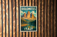A vintage-style poster of Dolomites, a famous mountain range in Italy, is displayed on a wooden wall.