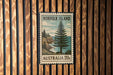A vintage postage stamp from Norfolk Island, Australia, featuring a pine tree and a coastal landscape.