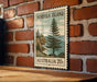 A vintage postage stamp from Norfolk Island, featuring a pine tree and a coastal landscape, is displayed on a brick wall.