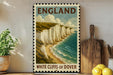A vintage-style poster of the White Cliffs of Dover, a famous landmark in England, displayed on a wall next to a wooden cutting board and some potted plants.
