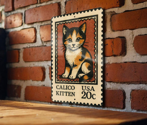 A metal sign featuring a calico kitten on a brick wall.
