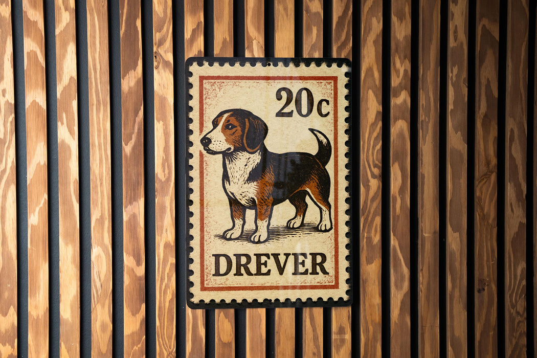 A metal sign with a dog illustration and the text "DREVER" is mounted on a wooden wall.