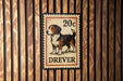A metal sign with a dog illustration and the text "DREVER" is mounted on a wooden wall.
