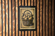 A framed illustration of a basket filled with pears is displayed on a wooden wall.