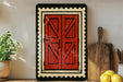 a wooden door with a red frame, hanging on a wall next to a wooden cutting board and a potted plant.
