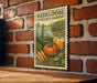 A vintage-style stamp or sign with illustrations of vegetables, such as carrots and pumpkins, is displayed on a brick wall.