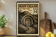 A framed image of a wooden door leading to a tunnel, with a vintage-style stamp design, is displayed on a shelf next to a wooden cutting board and a potted plant.