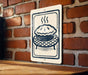 A sign featuring a pie on a brick wall, with steam rising from it, indicating that the pie is freshly baked.