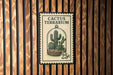 A Cactus Terrarium stamp is displayed on a wooden wall.