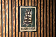 A sign with a ladder on it is mounted on a wooden wall.