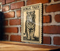 A framed illustration of a tiger is displayed on a brick wall.