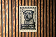 A black and white stamp-like sign with a dog illustration on it, mounted on a wooden wall.