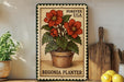 A metal sign with a floral design, featuring a potted plant with red flowers, is displayed on a shelf next to a wooden cutting board and a bowl of lemons.