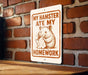 a sign with a cartoon hamster holding a piece of paper and the text "MY HAMSTER Ate MY HOMEWORK" on it.