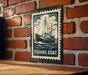 A sign with a fishing boat illustration is mounted on a brick wall.