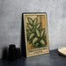 a metal sign with a plant illustration, placed on a table next to some black camera lenses.