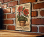 A poster of a begonia plant is displayed on a brick wall, with a wooden table below it.