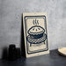 a sign with a pie illustration on it, placed on a countertop next to some black containers.