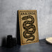 a sign with a snake design and the word "ANACONDA" printed on it, placed on a table next to some black camera lenses.