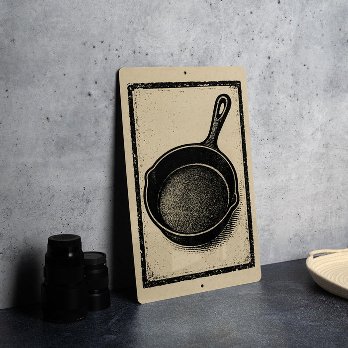 a black and white illustration of a frying pan on a wall, accompanied by a stack of black containers and a woven basket.