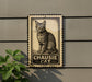 a metal sign with a cat illustration on it, mounted on a wall.