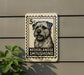 A black and white dog image on a postage stamp-like sign, mounted on a wall.
