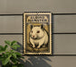 a metal sign with a hamster illustration on it, mounted on a wall.