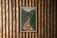a framed illustration of a stone path winding through a lush, green landscape.