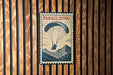 A vintage-style poster of a person paragliding is displayed on a wooden wall.
