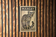 A framed image of a leopard cat, with the word "MARGAY" written above it, is displayed on a wooden wall.