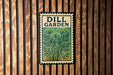 A vintage-style metal sign with the text "DILL GARDEN" displayed prominently in the center, surrounded by a green and yellow illustration of a dill plant.