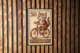 A postage stamp featuring a cat riding a bicycle, with the number 50 on it.