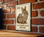 A metal sign featuring a rabbit illustration and the text "Netherland dwarf" is mounted on a brick wall.