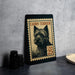 A framed image of a Cairn Terrier dog, which appears to be a postage stamp, is displayed on a table.