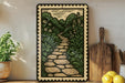 a decorative metal frame with a stone pathway leading through a lush, green garden scene.