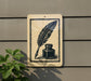a sign with a black and white illustration of a quill pen and inkwell, mounted on a wall.