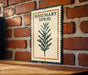 A metal sign with the word "ROSEMARY SPRIG" on it is hanging on a brick wall.