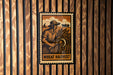 A vintage-style wheat harvest poster is displayed on a wooden wall, featuring a farmer holding a scythe and a field of wheat.