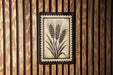 a wooden wall with a framed picture of wheat stalks.