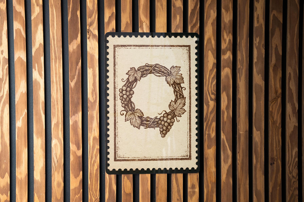 a wreath-like design with grapes and leaves, displayed on a wooden surface.