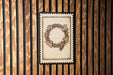 a wreath-like design with grapes and leaves, displayed on a wooden surface.