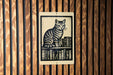 A sign featuring a cat sitting on a bookshelf with books below it.