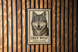 A framed image of a grey wolf is displayed on a wooden wall.