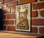 A wooden table with a wooden border, and a framed image of a cat on a brick wall.