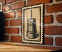 A metal sign with a black and white illustration of a wooden barrel is mounted on a brick wall.