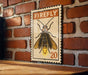 A vintage-style metal stamp featuring a detailed illustration of a firefly on a brick wall.