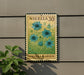 A metal sign with a floral design hangs on a wall, displaying the text "NIGELA 30" and "NIGELA GARDEN".