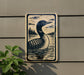 a sign depicting a loon swimming in a lake, with a forest in the background.