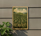 a framed illustration of a rural landscape with a field of trees and rolling hills, mounted on a wall.