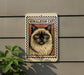a sign with a picture of a Himalayan cat on it, mounted on a wall.